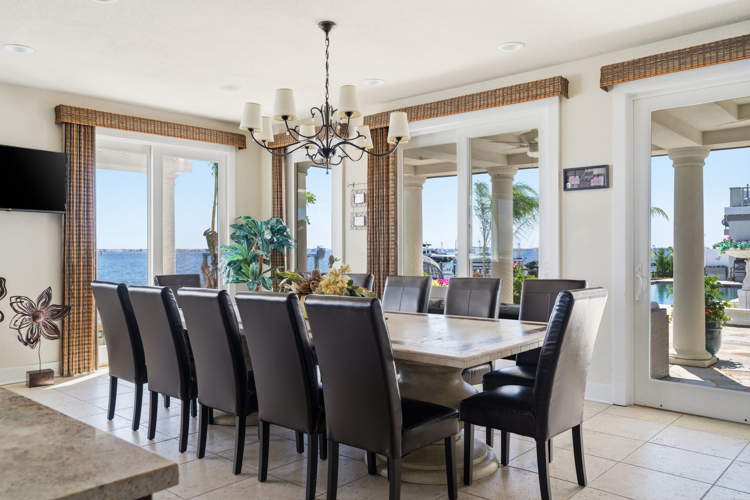dining room with seating for ten beneath a chandelier and multiple sliding glass doors to the waterfront patio