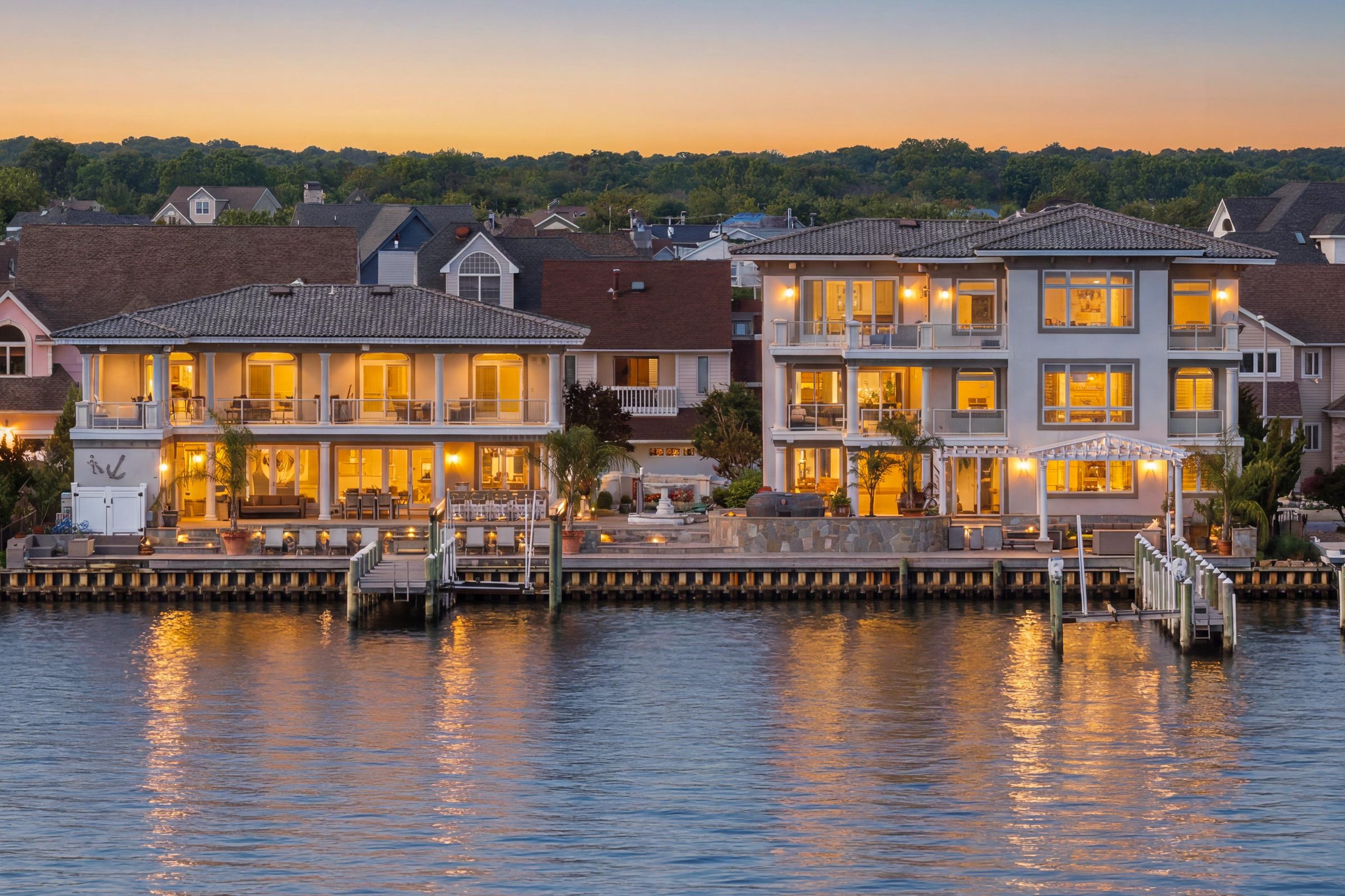 twilight view of both residences illuminated along the water with docks visible