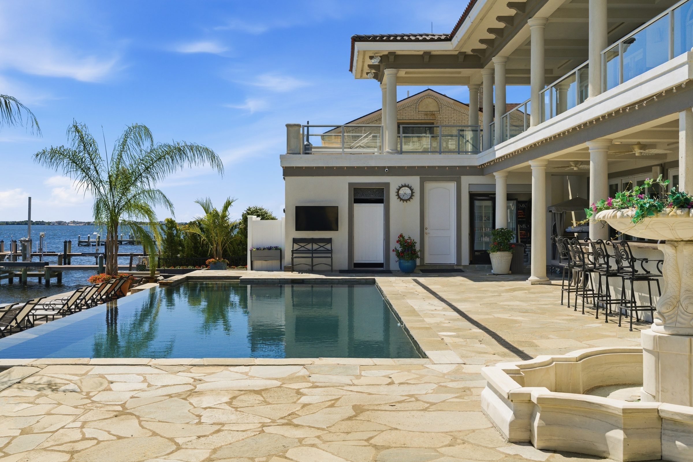 pool patio and outdoor kitchen bar area beside the infinity pool