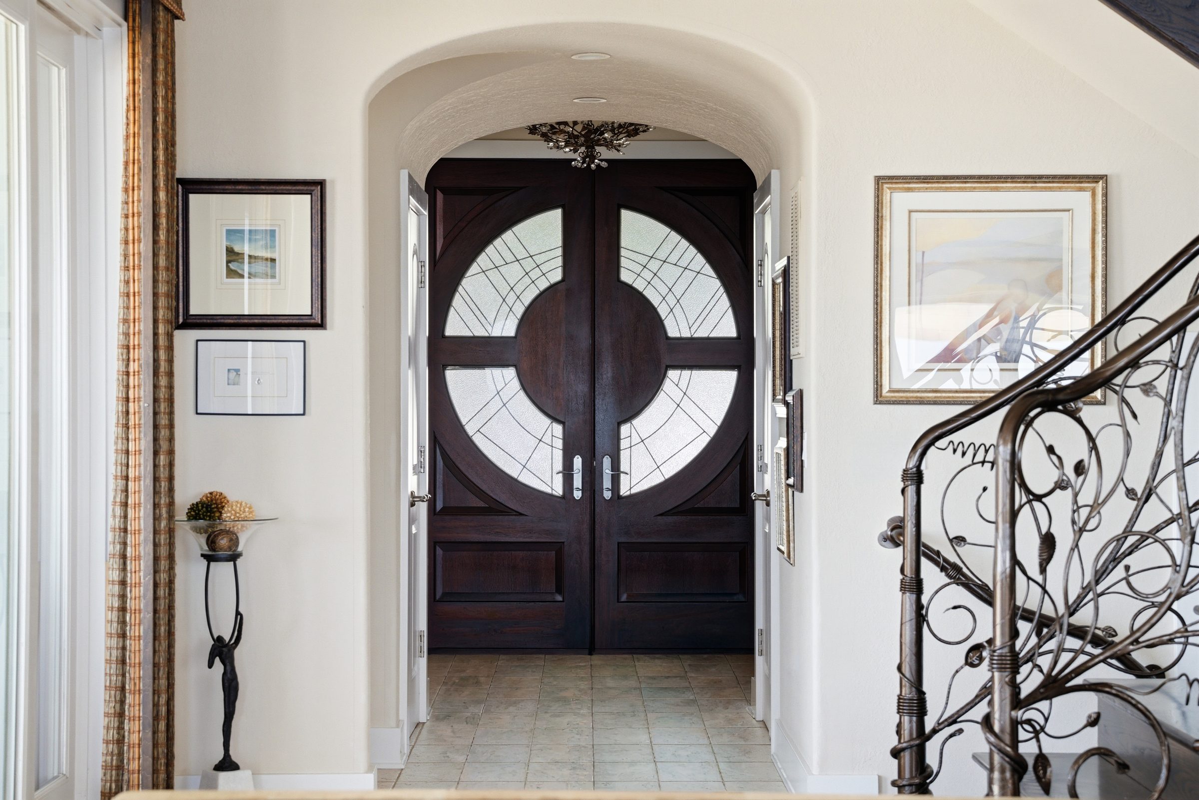 arched double-door entry foyer with wrought-iron staircase rail