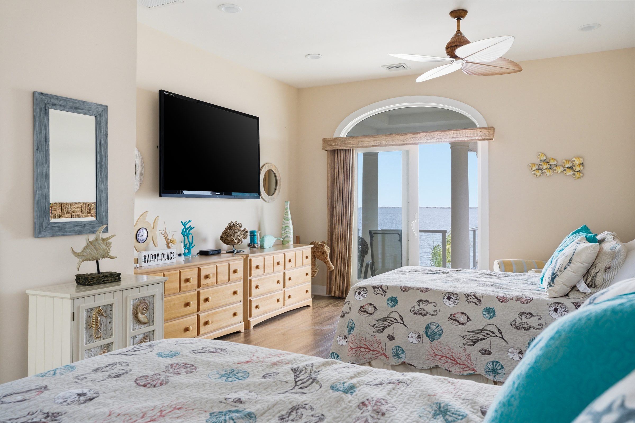 guest house bedroom with twin beds, seashell-pattern quilts and private balcony overlooking the water