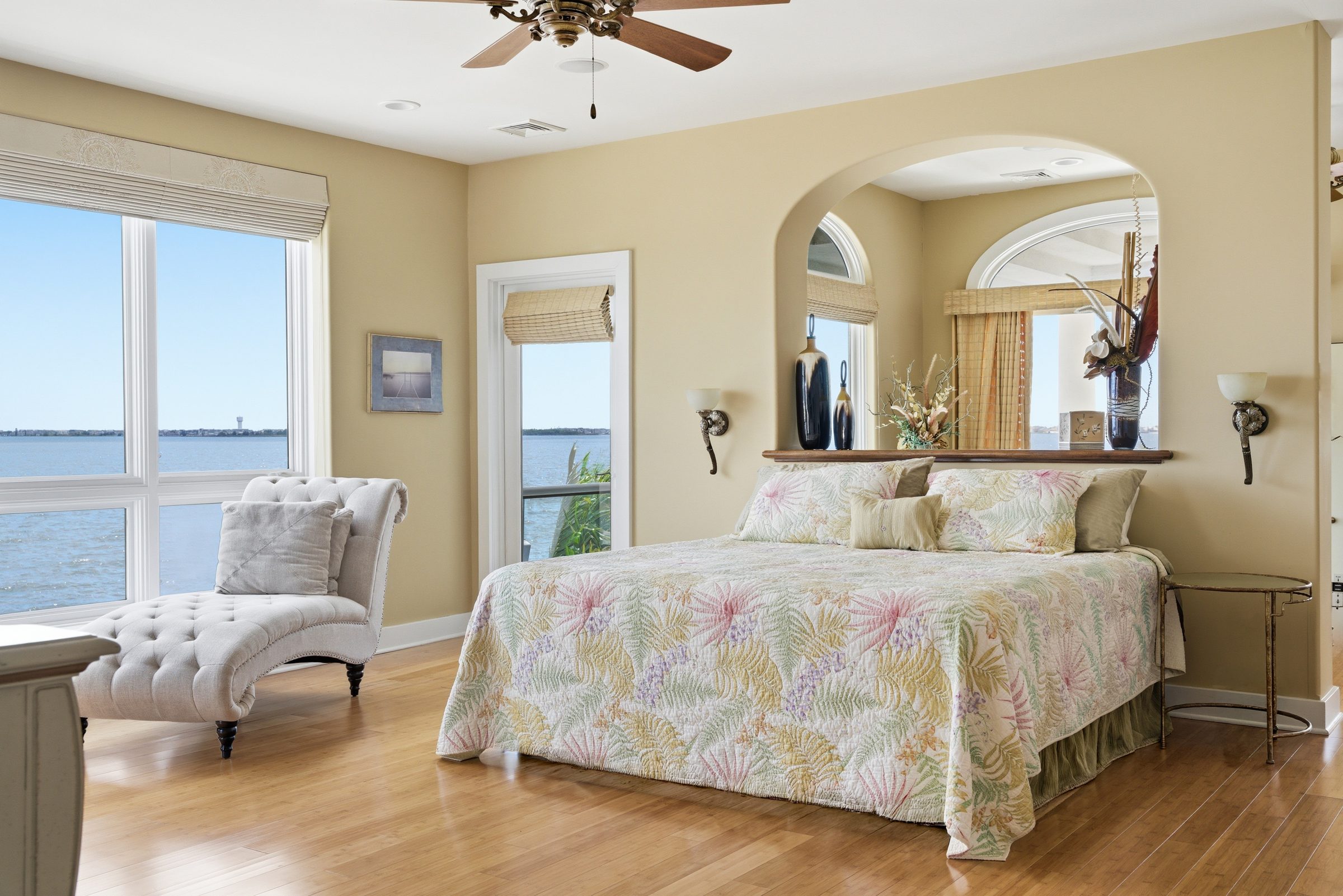 primary bedroom with floral bedding and balcony access overlooking the water